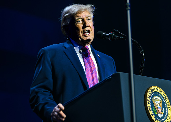 Donald Trump at a podium, speaking loudly about Rosie O'Donnell's claims.