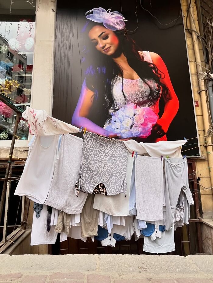 A candid moment from the streets: laundry hangs on a line in front of a large billboard of a woman.