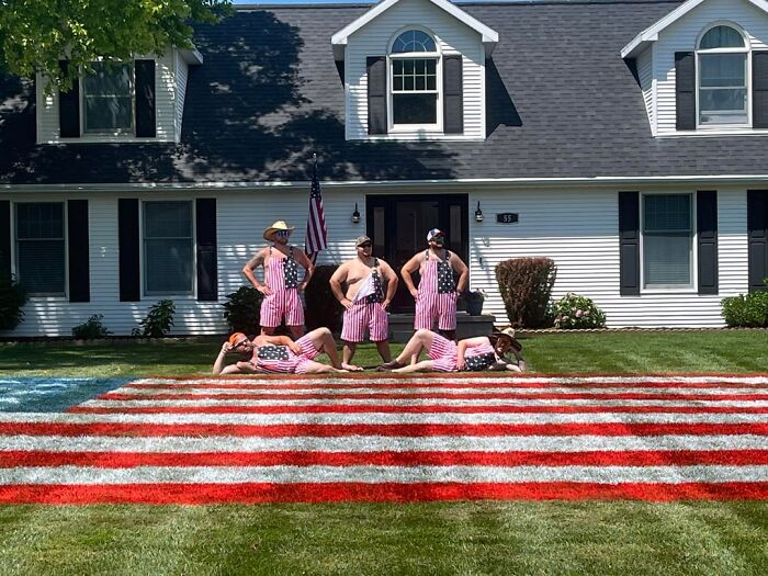Neighbors dressed in USA flag overalls lying on an American flag painted on a lawn, interesting neighbors.