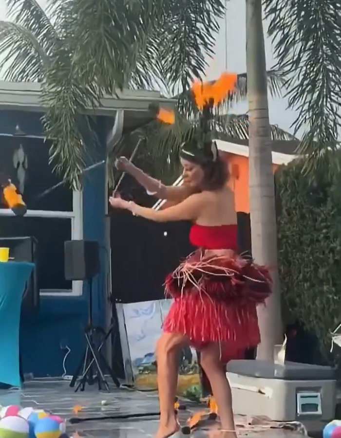 A woman in a red skirt and top performing with fire, showcasing her skirt mid-performance as it starts to catch fire. A woman in a red skirt and top performing with fire, showcasing her skirt mid-performance as it starts to catch fire.