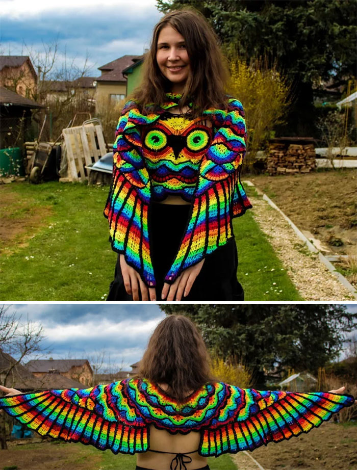 A woman wearing a vibrant, rainbow-colored crocheted owl shawl, showcasing a unique handmade project.