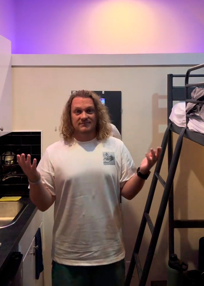A man in his 90-square-foot NYC apartment with a bunk bed and kitchen, showing the harsh reality of small living. A man in his 90-square-foot NYC apartment with a bunk bed and kitchen, showing the harsh reality of small living.