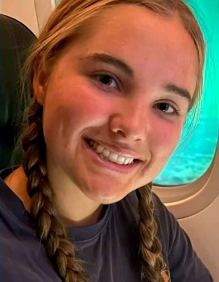 Close-up of a smiling missing teen girl with braids, inside an airplane, before her tragic finding.