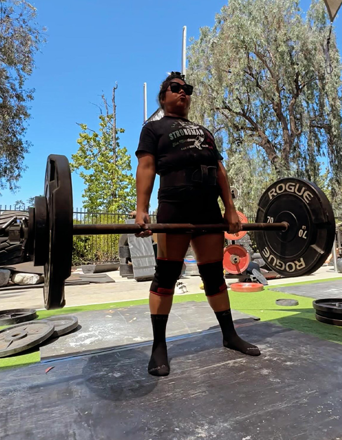 A strength athlete, 41, performs a deadlift with a barbell, showcasing her strength before losing arms and legs.