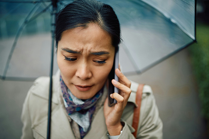 A woman makes her friend of 20 years suffer by calling her on the phone in the rain, looking concerned. A woman makes her friend of 20 years suffer by calling her on the phone in the rain, looking concerned.