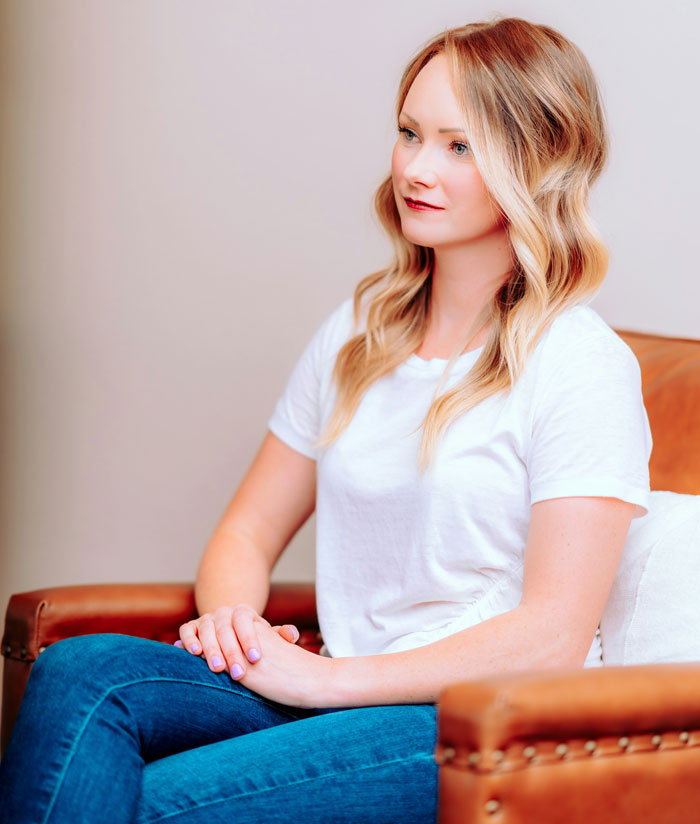 A woman sitting on a brown leather chair, looking to the side, representing women who weren't wife material.