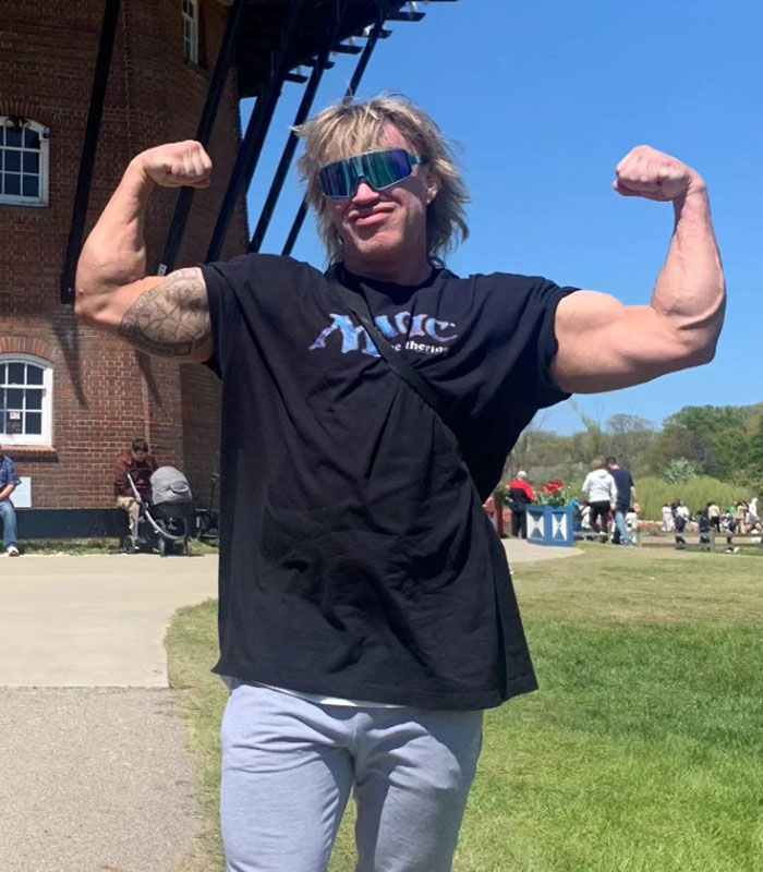 Influencers exposed for lying: A man flexing his muscles outdoors, wearing sunglasses and a black t-shirt.