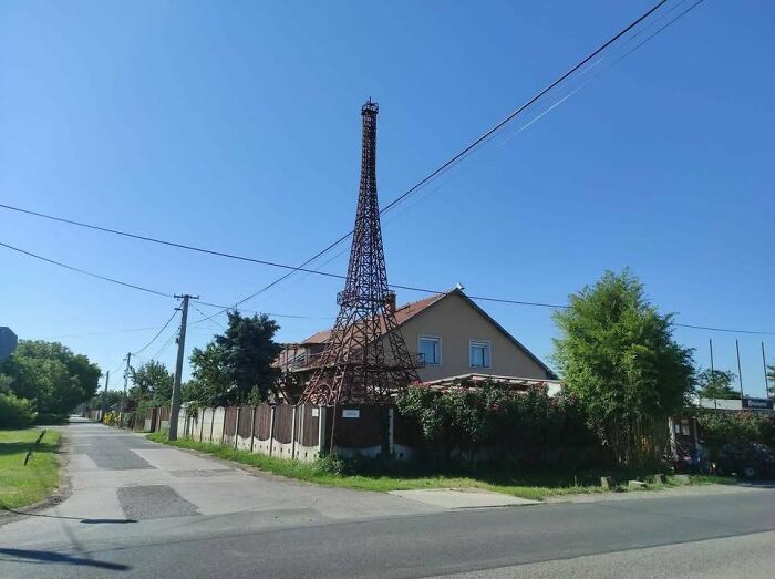 A house with a large miniature Eiffel Tower in its yard, highlighting why people from Eastern Europe are built different.