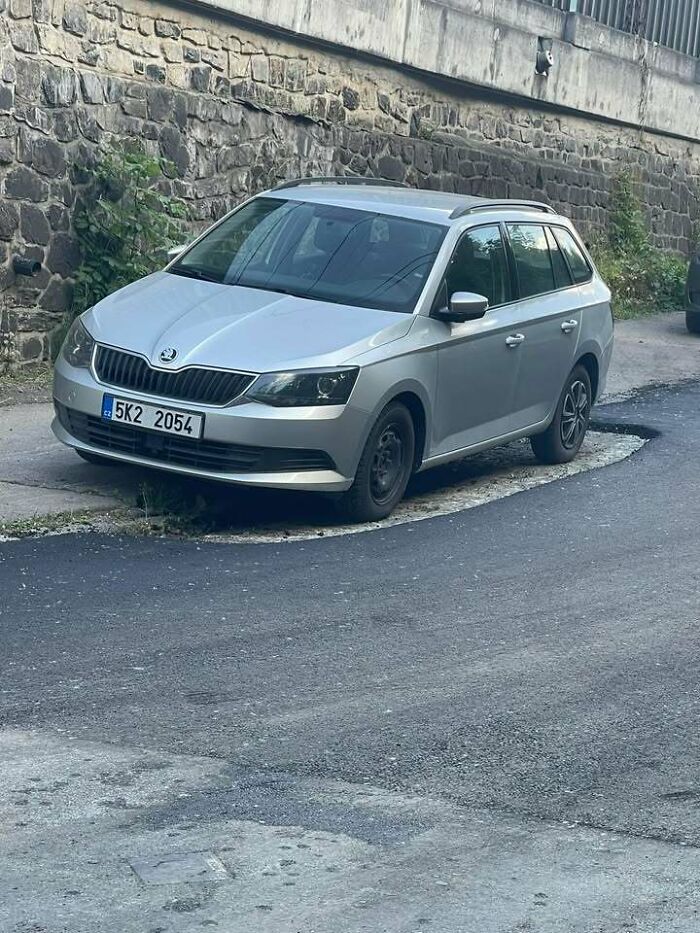 A silver car parked on a damaged road, showcasing why people from Eastern Europe are built different.