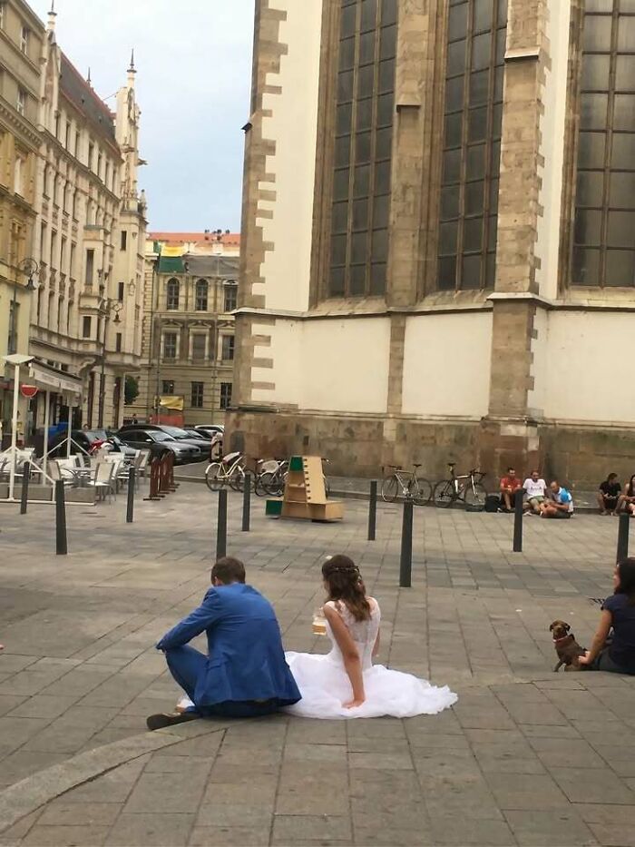 Bride and groom sitting on the ground in Eastern Europe, enjoying a moment, showing people are built different.