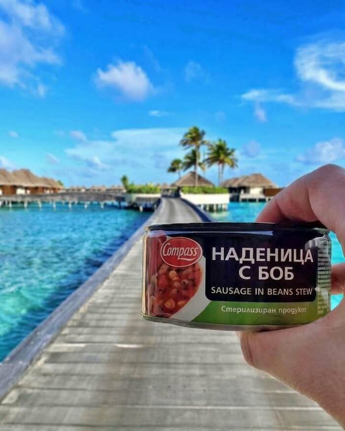 Eastern Europe men built different, holding a can of sausage in beans stew with an ocean background.