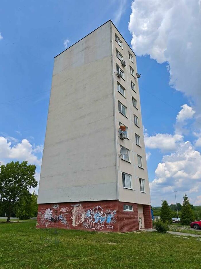 An image of a tall, narrow building from Eastern Europe with graffiti on the base, showing unique architecture.