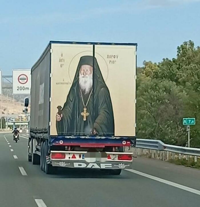 A truck on a highway with a large religious icon painted on its back, representing people from Eastern Europe.