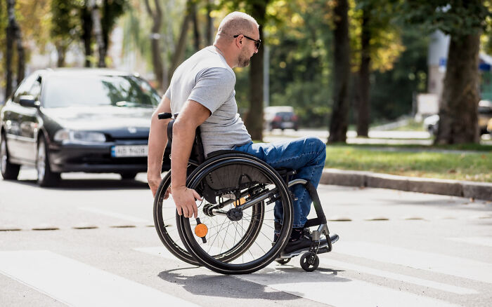 A man in a wheelchair crossing the street, highlighting some dumb reasons couples divorce.