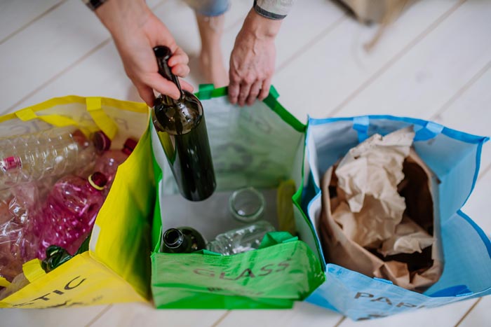 A person sorting glass, plastic, and paper into separate bins, highlighting dumb work rules about recycling.