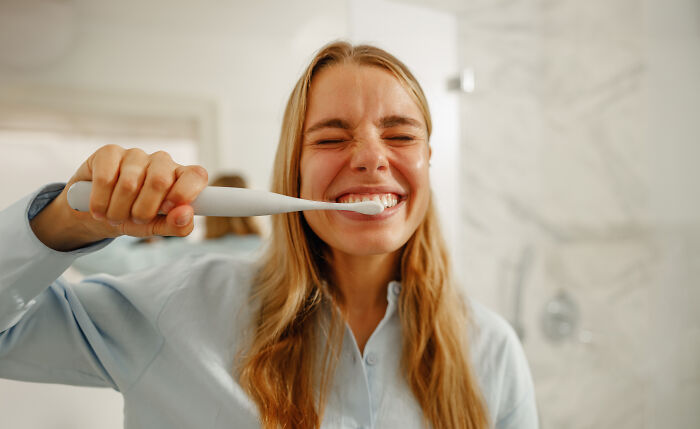 A woman brushes her teeth, indicating good oral health. Oral hygiene is a crucial part of maintaining healthy habits.