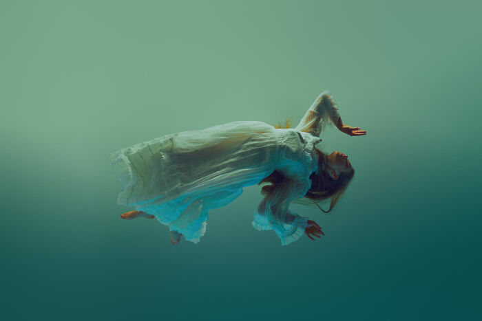 Woman floating in ethereal green water, symbolizing the mysterious line between life and what comes after.