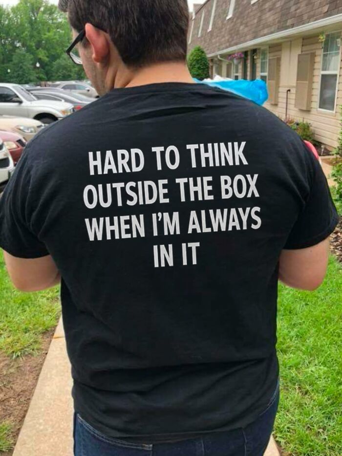 A person from behind wears an iconic shirt that says: 'Hard to think outside the box when I'm always in it.'