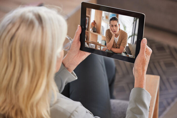 Elderly woman in therapy session on a tablet, looking at her unhappy therapist, discussing why they walked out without therapist.