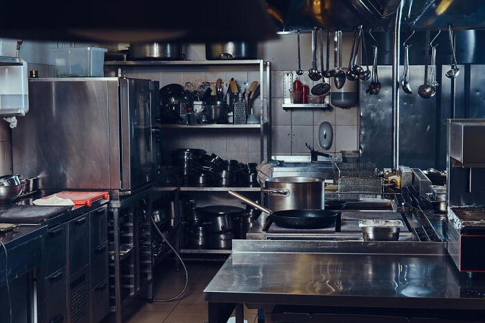 A busy commercial kitchen with stainless steel surfaces and various cooking equipment, hinting at employee stories.