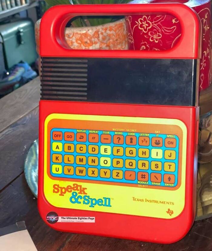 A red Texas Instruments Speak & Spell, a popular educational toy from the '80s, displayed on a surface.