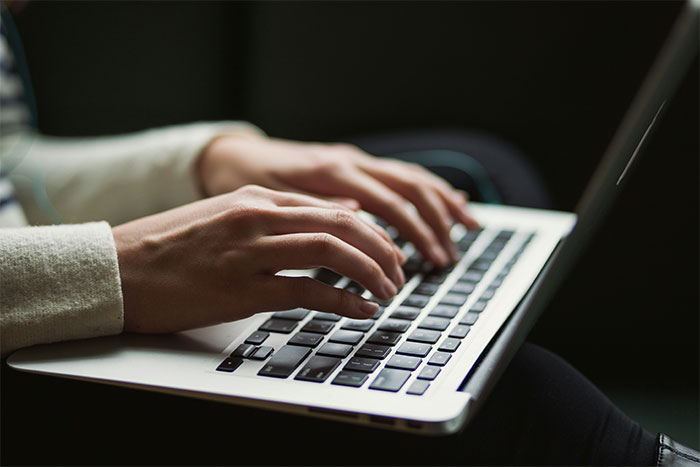 Close-up of a person's hands typing on a laptop, symbolizing online discussion about a woman ignoring boundaries.