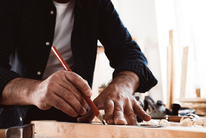 A man marking wood with a pencil and ruler. Doctors refuse to do certain things after seeing them go wrong.