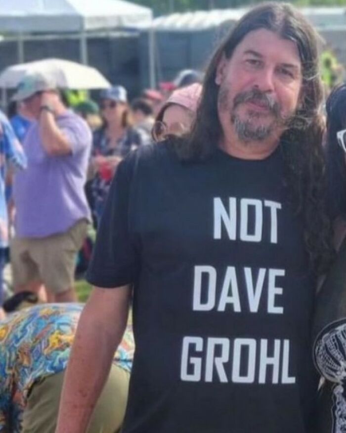 A man with long hair and a beard wearing a black shirt that reads 'NOT DAVE GROHL', one of many iconic shirts.