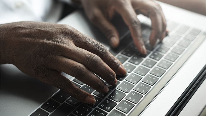 A person's hands typing on a laptop keyboard, representing the story of a woman moving into a guy's house and defying boundaries.