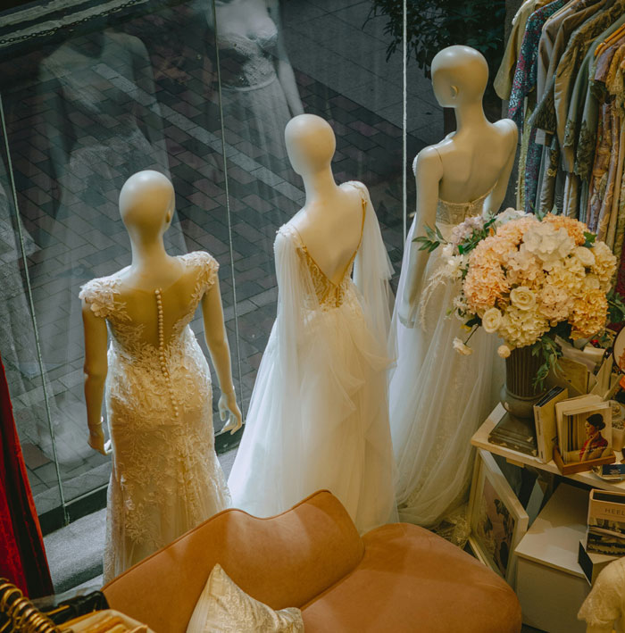 Mannequins displaying elegant wedding dresses in a shop window, showcasing the attire at weddings.