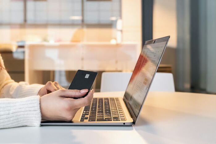 A person holding a credit card while typing on a laptop, illustrating industry secrets of online transactions.