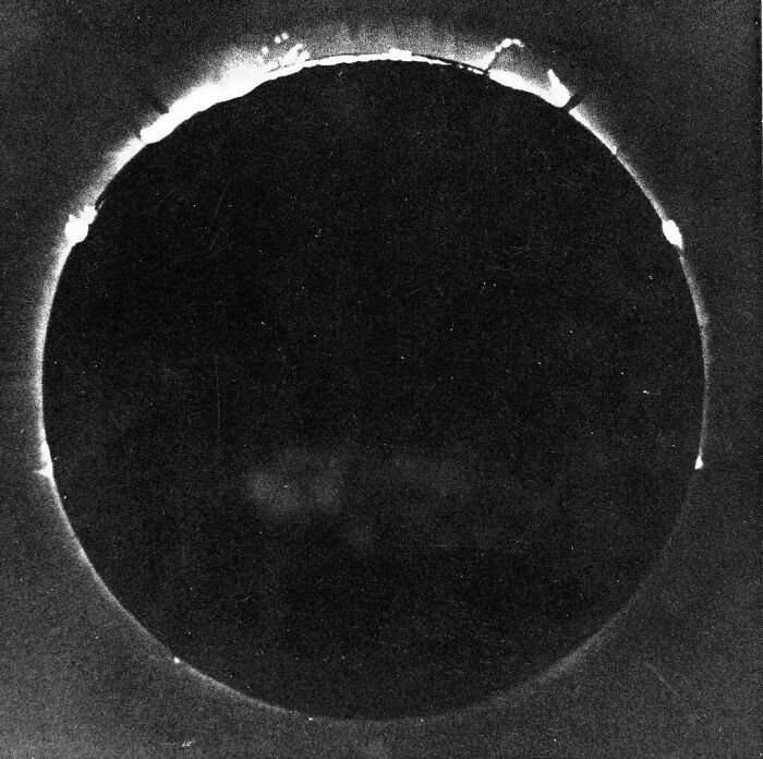 An old, dark solar eclipse photo with a subtle corona, an extraordinary historical event captured over years.