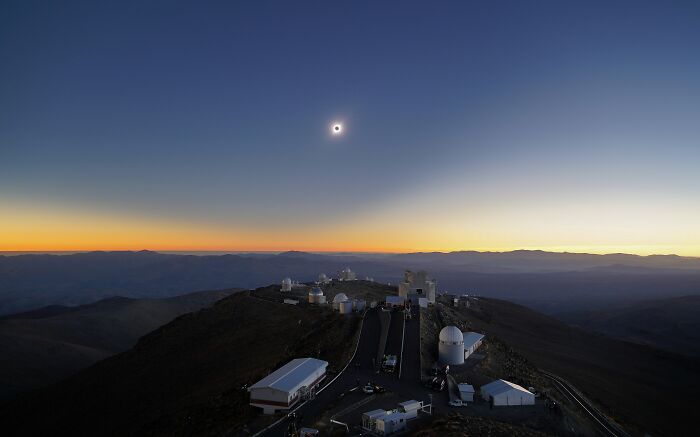 Extraordinary solar eclipse photo above an observatory on a mountain at sunset, making history.