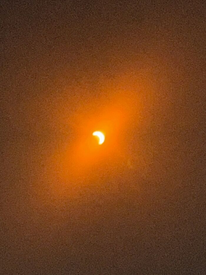 Extraordinary solar eclipse photo showing a crescent sun in a fiery orange sky, making history.