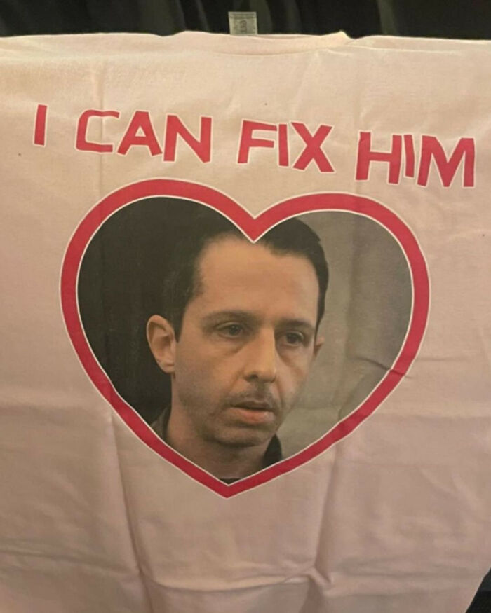 A close-up of an iconic shirt with a heart around a man's face, saying I Can Fix Him.