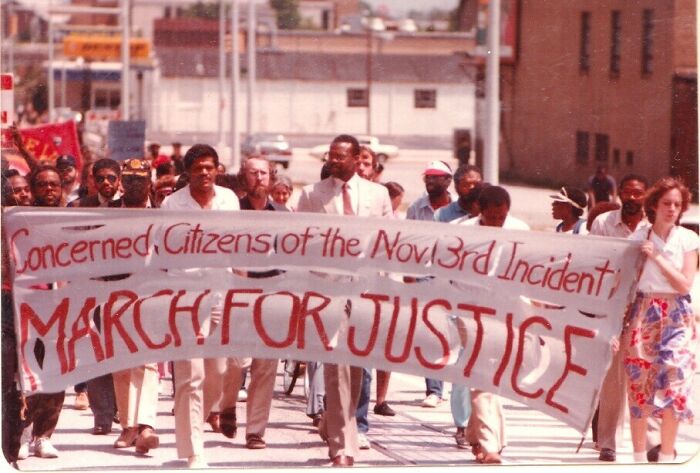 A crowd of people marching for justice, holding a banner, a rare and fascinating photo from American history.