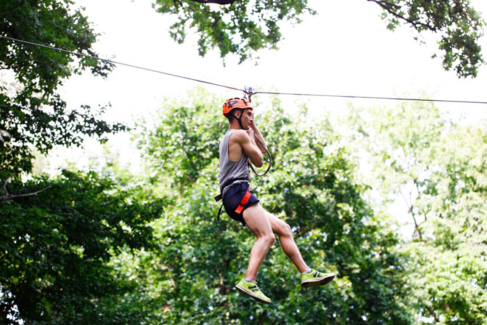 A man zip-lining through trees, describing an unhinged way of fun.