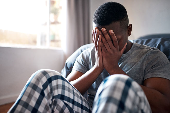 A man with his face in his hands, expressing frustration over a woman moving into his house and ignoring his boundaries.