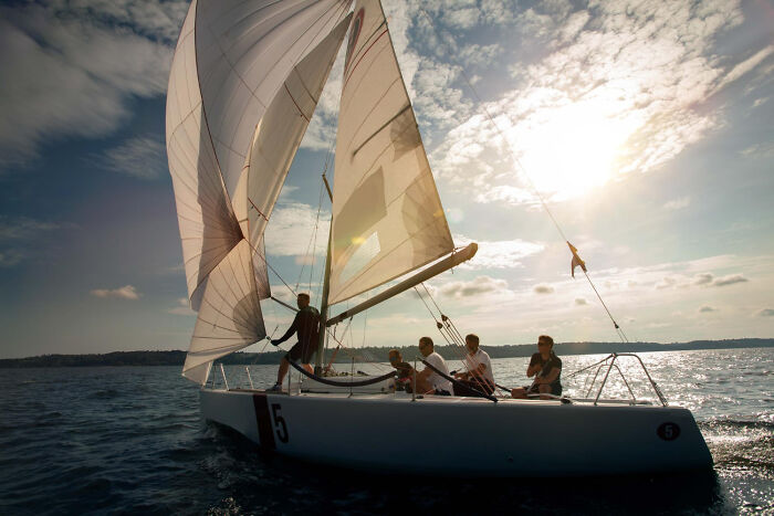People on a sailboat under a sunny sky, capturing incredible stories about life and adventure.