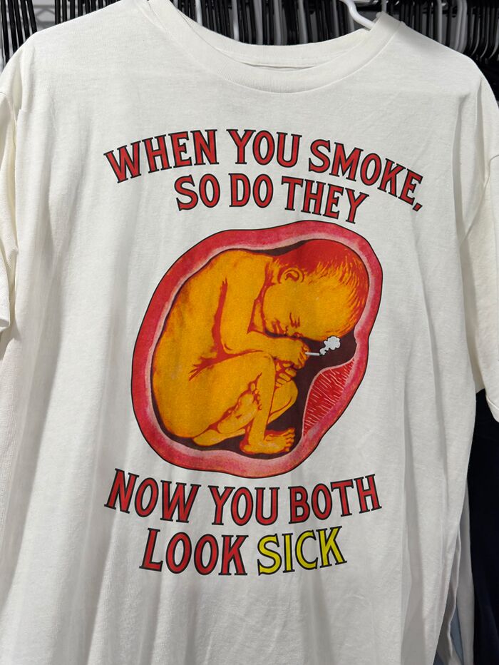 A white t-shirt with an illustration of a fetus smoking, conveying iconic shirts message against smoking.