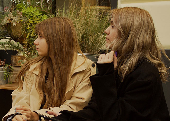 Two women with long hair looking away from the camera, perhaps on a worst first date with women.