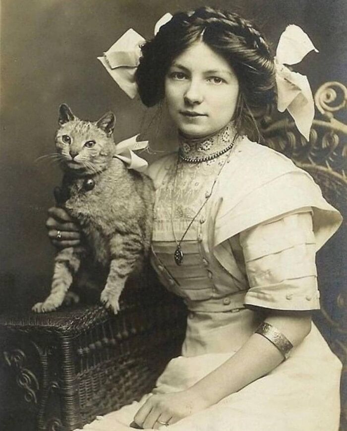 A vintage photo of a woman posing with her cat, showing how animals have always stolen the spotlight.
