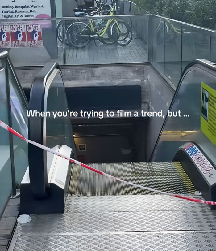 A metro station escalator blocked by red and white tape, with a sign for art and bicycles above, part of the metro station hero story. A metro station escalator blocked by red and white tape, with a sign for art and bicycles above, part of the metro station hero story.