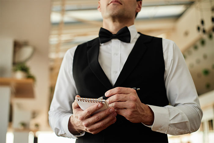 A waiter taking an order, illustrating the couple's dinner experience and their neighbors' intentions to pay their bills. A waiter taking an order, illustrating the couple's dinner experience and their neighbors' intentions to pay their bills.