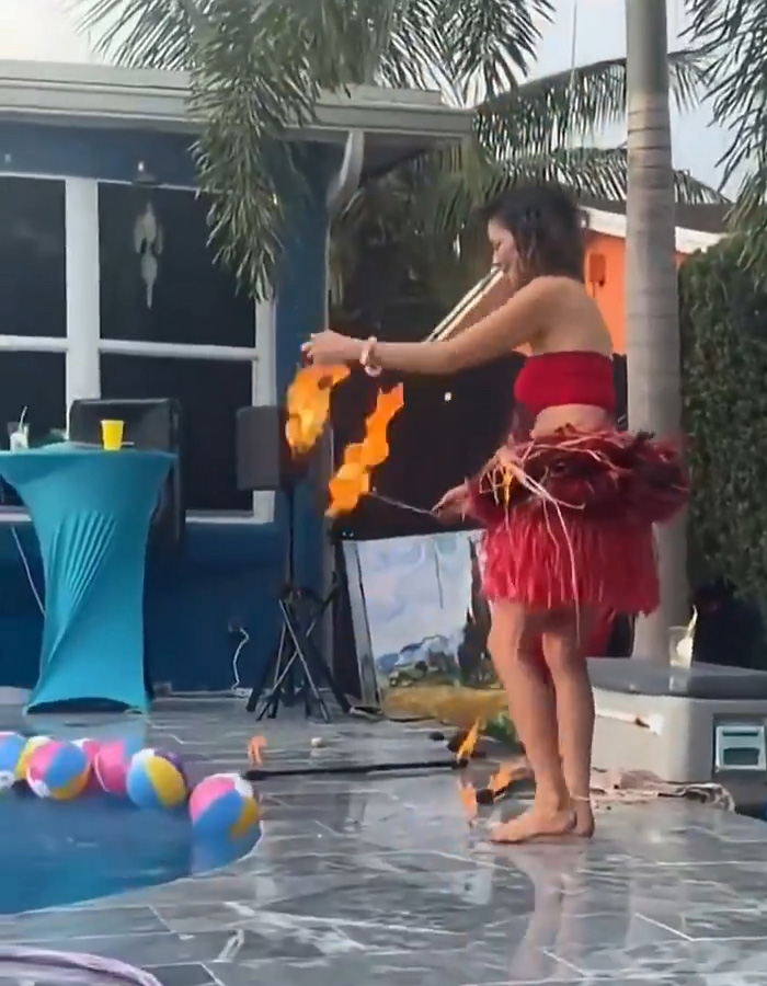 A woman doing a fire performance, with her skirt catching fire, highlighting the mid-performance incident. A woman doing a fire performance, with her skirt catching fire, highlighting the mid-performance incident.