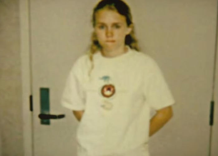 A young woman who escaped a serial criminal after 18 hours of captivity, appearing serious.