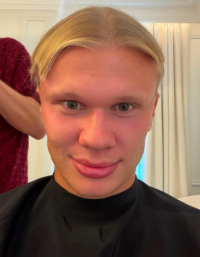 Erling Haaland before his haircut, smiling at the camera with his blond locks. Erling Haaland before his haircut, smiling at the camera with his blond locks.