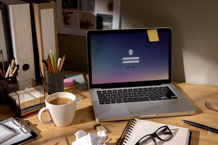A desk with a laptop displaying a login screen, symbolizing dumb work rules around technology use.
