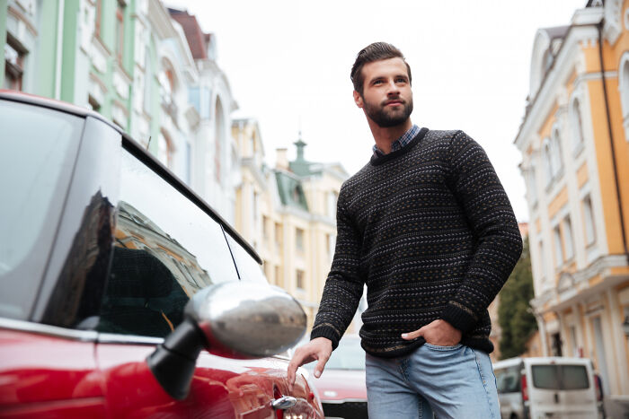 A man standing next to a car, illustrating a scenario from shocking employee stories that got someone fired.