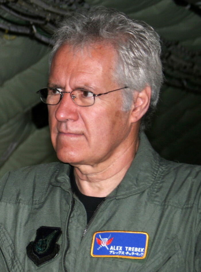 Alex Trebek, a celebrity, wearing glasses and a uniform with his name patch.